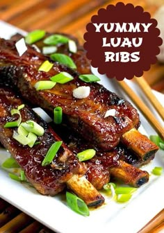 two pieces of meat on a plate with chopsticks next to it and garlic