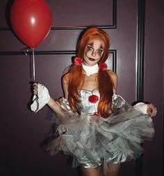 a woman dressed up in a costume holding a red balloon