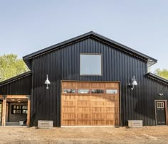 a large black barn with wooden doors and windows