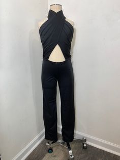 a mannequin with a black top and pants on display in front of a white wall