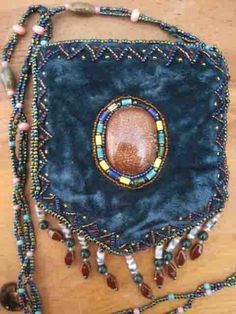 a blue purse with beads and beading on the bottom is sitting on a wooden table