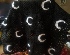 a black crocheted blanket with white circles on it