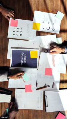 several people at a table with papers and pens on top of each other that have sticky notes attached to them