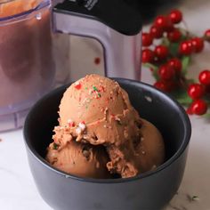 two scoops of chocolate ice cream in a black bowl next to a blender