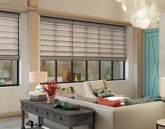 a living room filled with furniture and windows covered in roman blind shades on top of them