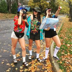 three young women standing on the side of a road with their arms in the air