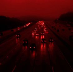 a red sky filled with lots of traffic on top of a highway next to trees