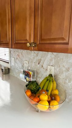 a bowl filled with fruit sitting on top of a kitchen counter