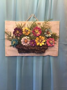 a piece of wood with flowers on it hanging from a curtain behind a drape