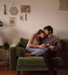 a man and woman sitting on a green couch