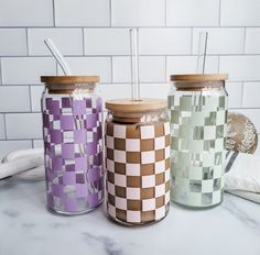 three jars with toothbrushes in them sitting on a counter next to each other