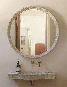 a bathroom sink with a mirror above it and a vase on the counter next to it