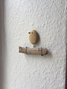 a small wooden bird sitting on top of a piece of wood next to a wall