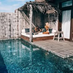 two people sitting on a bed in the middle of a swimming pool with an overhang