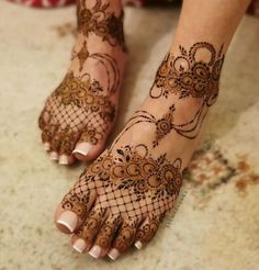 the feet and hands of a woman with henna tattoos