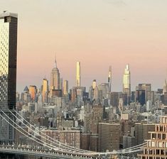 the city skyline is seen from across the water with a bridge in front of it