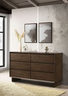 a large wooden dresser with two pictures on the wall above it and a vase filled with flowers