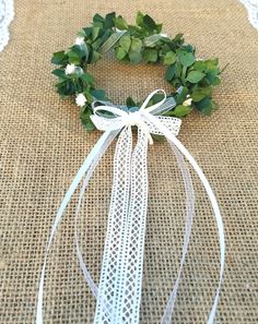 a close up of a wreath on a burlap table cloth with white ribbon