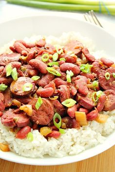 a white bowl filled with rice and meat on top of a wooden table next to chopsticks