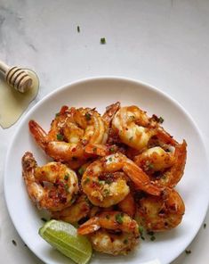 a white plate topped with shrimp next to a slice of lime