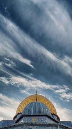 the dome on top of an ornate building under a cloudy blue sky with wispy clouds