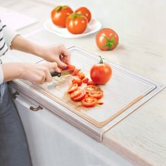 a person cutting tomatoes on a cutting board