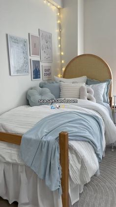 a bed with white sheets and blue comforter in a room decorated with pictures on the wall