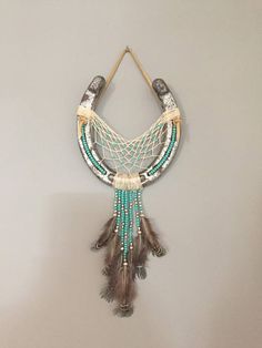 a necklace with beads and feathers hanging on a wall