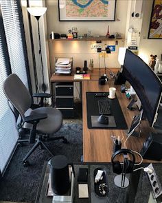 a desk with a computer monitor, keyboard and headphones sitting on top of it