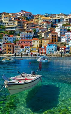 a boat floating on top of the ocean next to a shore filled with lots of houses