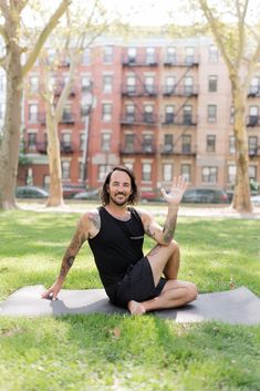 a man sitting on top of a yoga mat in the grass