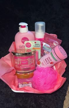 a basket filled with lots of pink items on top of a black table next to a bottle