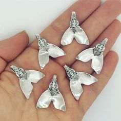 six silver butterfly charms sitting on someone's palm in front of the camera,