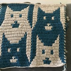 a crocheted blue and white pillow with cats on it's sides sitting on a couch