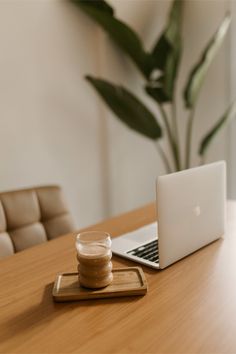 a laptop computer sitting on top of a wooden table next to a jar of peanut butter