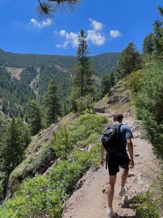 a man with a backpack is walking up a trail in the mountains on a sunny day