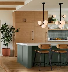 a kitchen with wooden cabinets and stools next to an island counter top in front of a potted plant