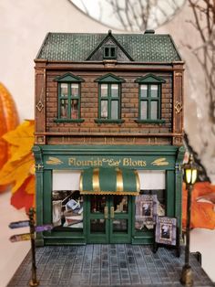 a doll house on display in front of a storefront with autumn leaves around it