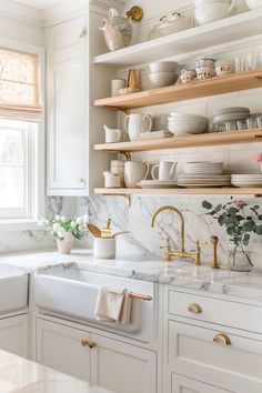 a kitchen with white cabinets and marble counter tops, gold faucets and open shelving