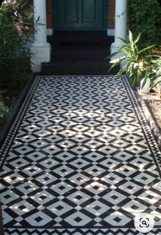 a black and white tiled walkway in front of a green door