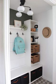 an entryway with white shelves and black baskets on the floor next to a checkered tile floor