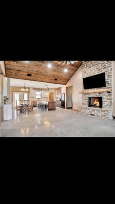 a large open living room with a stone fireplace and flat screen tv mounted to the wall