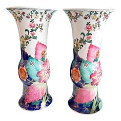 two vases with flowers painted on them, one is blue and the other is pink