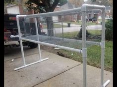 a metal fence with white posts and wire on the side of a sidewalk in front of a house