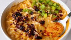 a white bowl filled with noodles and vegetables on top of a marble counter topped with a spoon