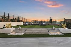 an outdoor area with grass, plants and sculptures in the background at sunset or dawn