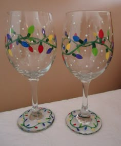 two wine glasses sitting on top of a table covered in confetti and lights