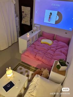 a bed with pink sheets and pillows in front of a projector screen that says it's you