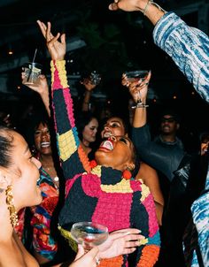 a group of people standing next to each other at a party with their hands in the air