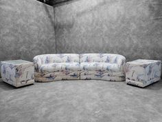 a couch and two stools are in a room with concrete walls on either side